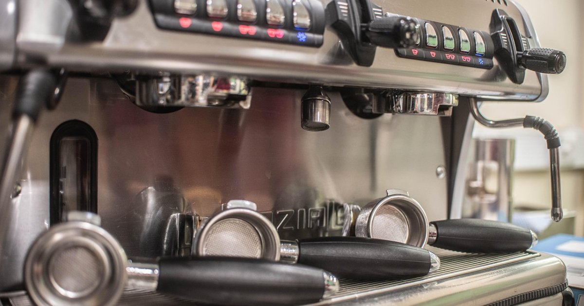 Espresso machine group heads with portafilters resting on the drip tray